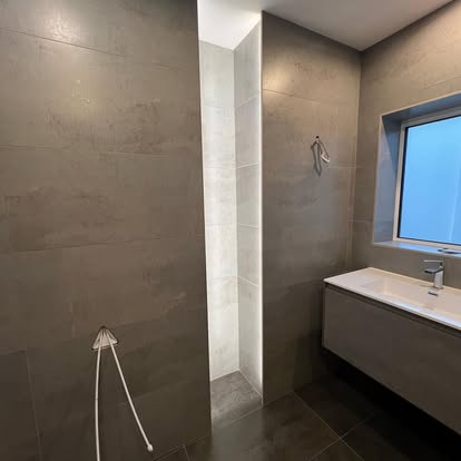 A tiled bathroom with a lit recess and a wall-hung vanity unit