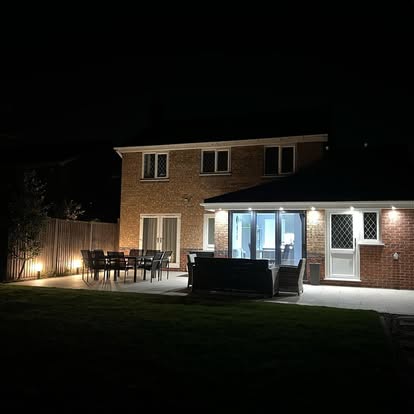 The back of a house lit at night by exterior lighting