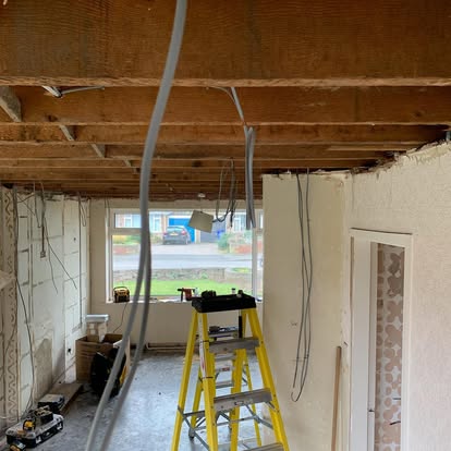 A room stripped back during a renovation, with cables run and a stepladder