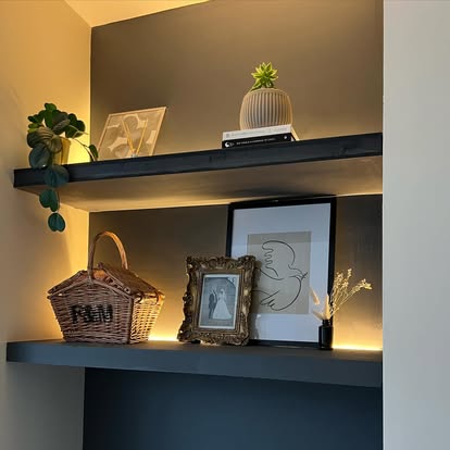 Strip lighting under floating shelves against dark paint